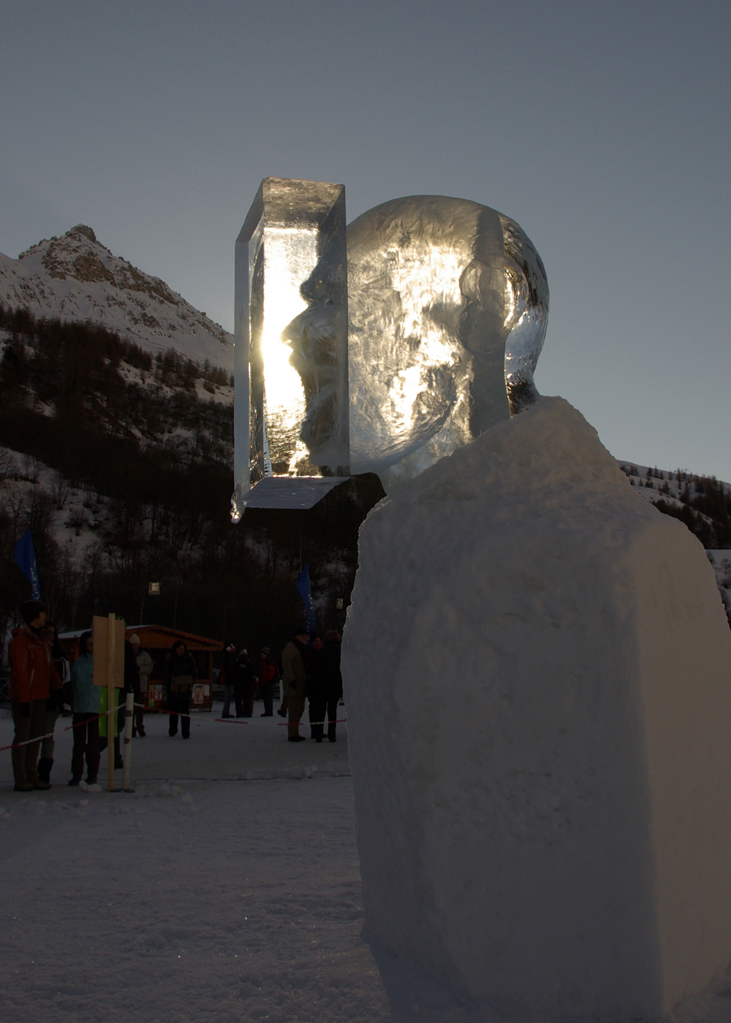 photo de la sculpture sur glace représentant une tête d'homme qui crie, son visage est pris dans un bloc de glace, mais on le voit par transparence.
L'on peut voir le visage deux ou trois fois par reflet sur les différentes faces du cube.
Ici un jeu de lumière s'opère qui donne l'impression que le son du cri reste coincé dans le cube.